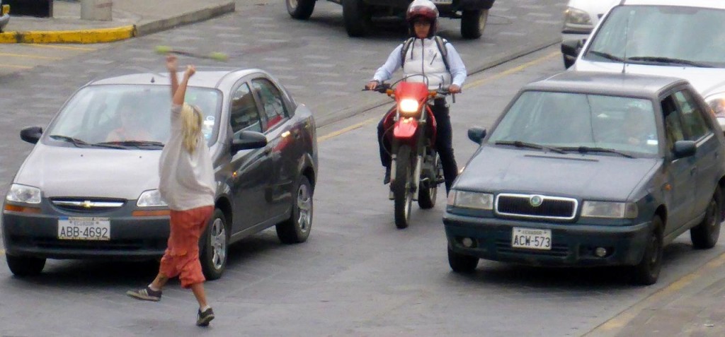 She's working the streets. It is very common throughout Latin America to see street performers at traffic stops. They then collect change from drivers. 