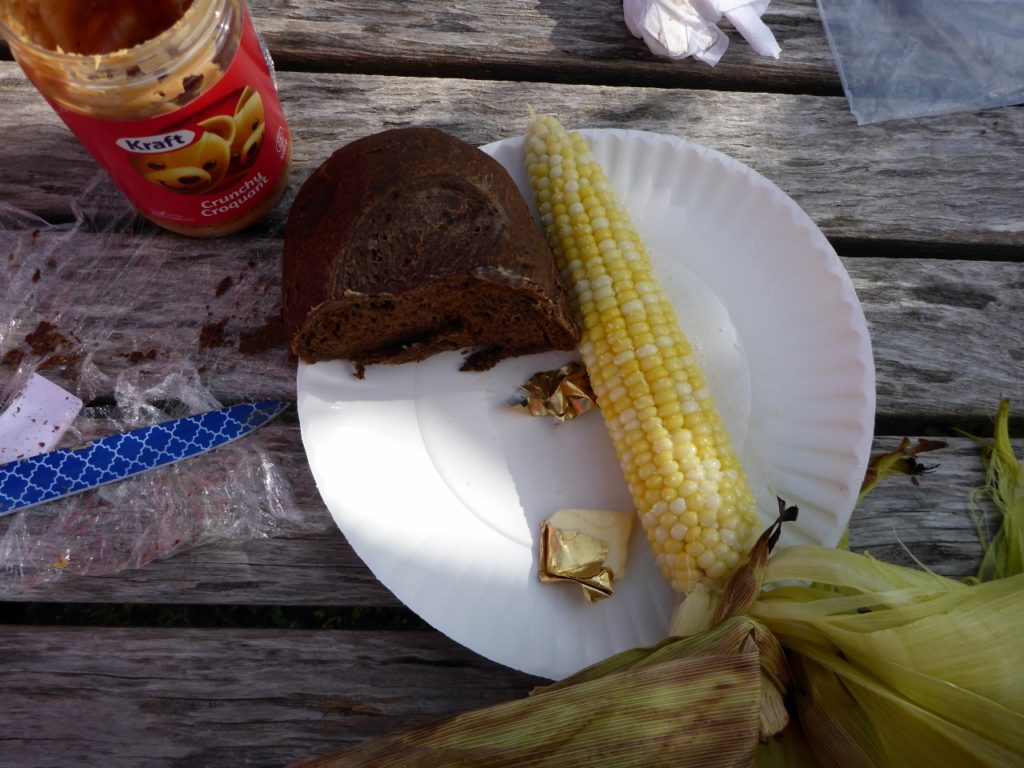 A delicious lunch at a farm. Fresh pumpernickel bread, peanut butter, and roasted corn.