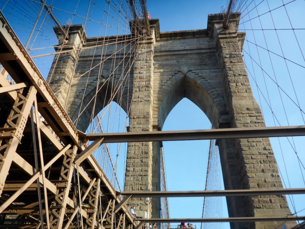 The Brooklyn Bridge is a hybrid cable-stayed/suspension bridge in New York City and is one of the oldest bridges of either type in the United States. Completed in 1883, it connects the boroughs of Manhattan and Brooklyn by spanning the East River.